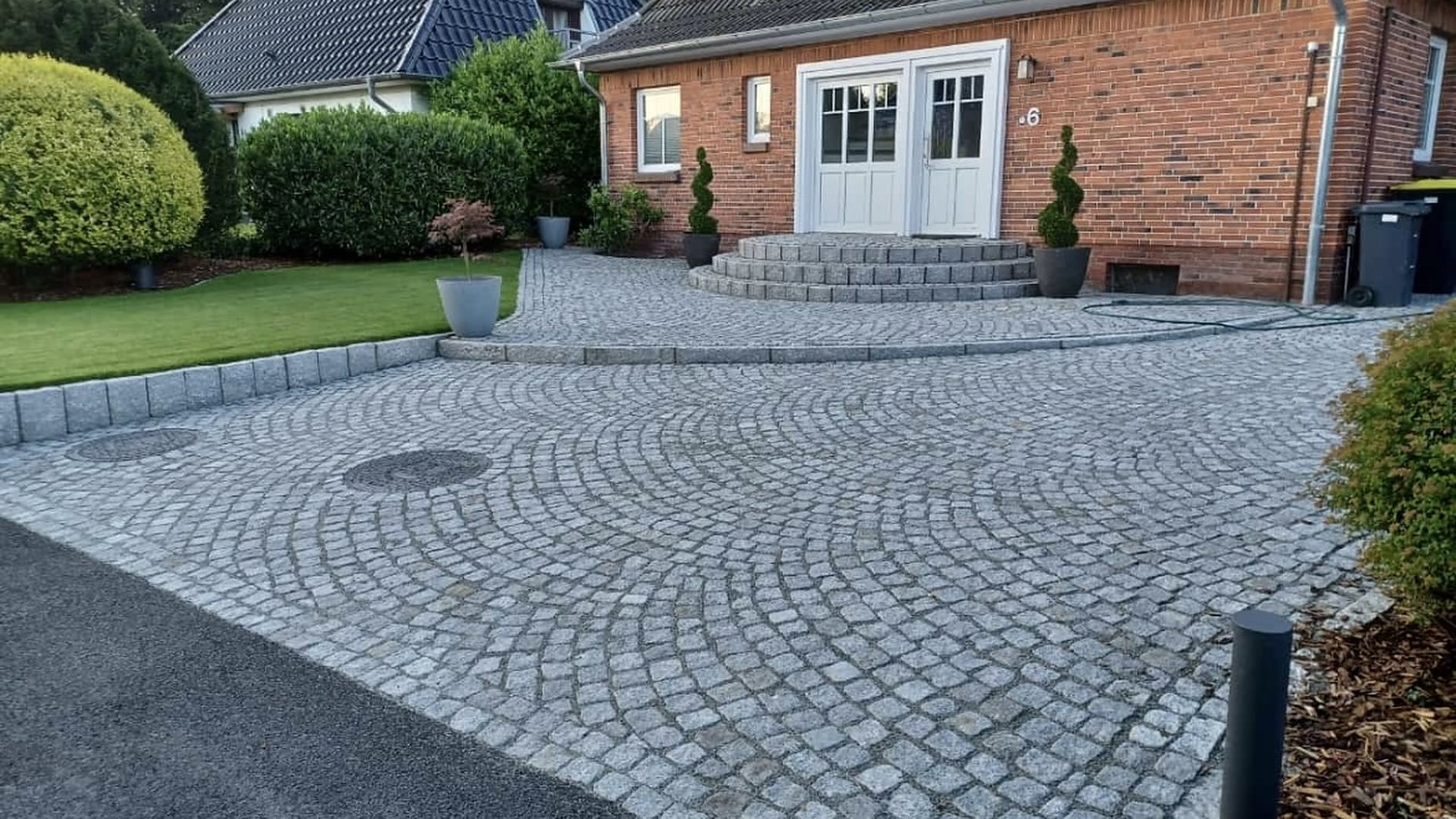 Einfahrt in Kleinpflaster mit rundem Pflastermuster vor einem Klinkerhaus