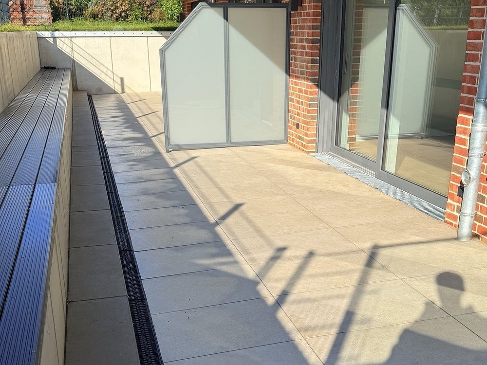 Terrasse aus großformatigen hellen Platten an einer Glasfassade