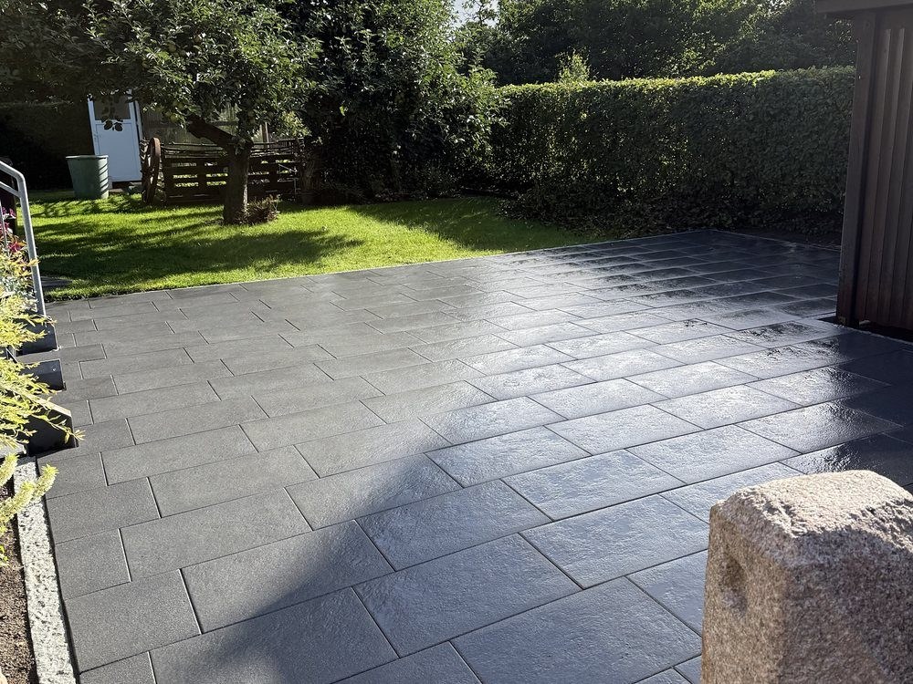 Terrasse aus dunklen Großformatplatten im Garten