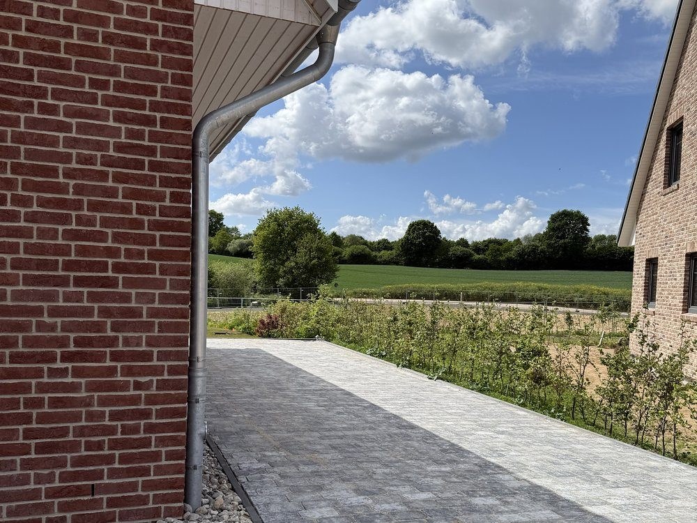 Zuwegung aus Betonpflaster entlang einer Klinkerfassade